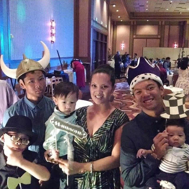 Group of people in hats posing for photo at an event; indoor setting with other attendees.