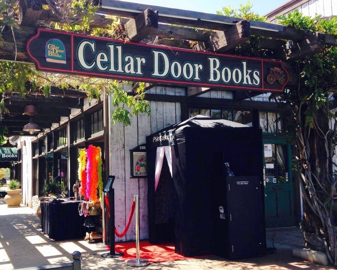 Cellar Door Books storefront with a black photo booth, red carpet, and colorful feather boa decorations.