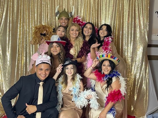 Group of people in costumes posing in front of a gold backdrop. They have fun expressions and wear feather boas and hats.