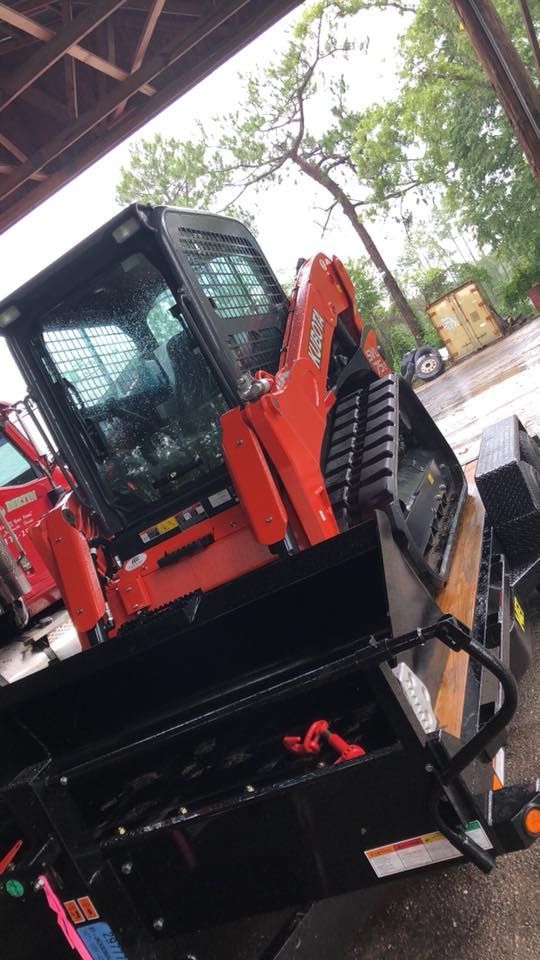 Orange Kubota skid steer loader with black bucket on a trailer.