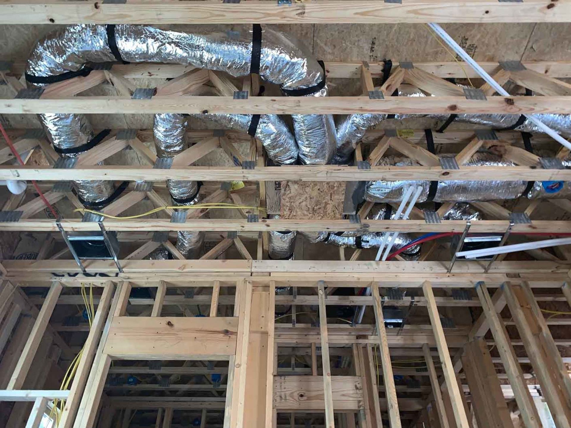 the ceiling of a house under construction with a lot of pipes coming out of it .