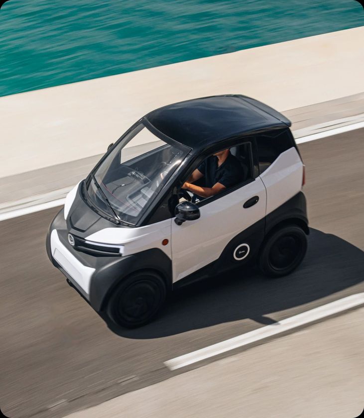 Una piccola automobile bianca e nera sta percorrendo una strada.