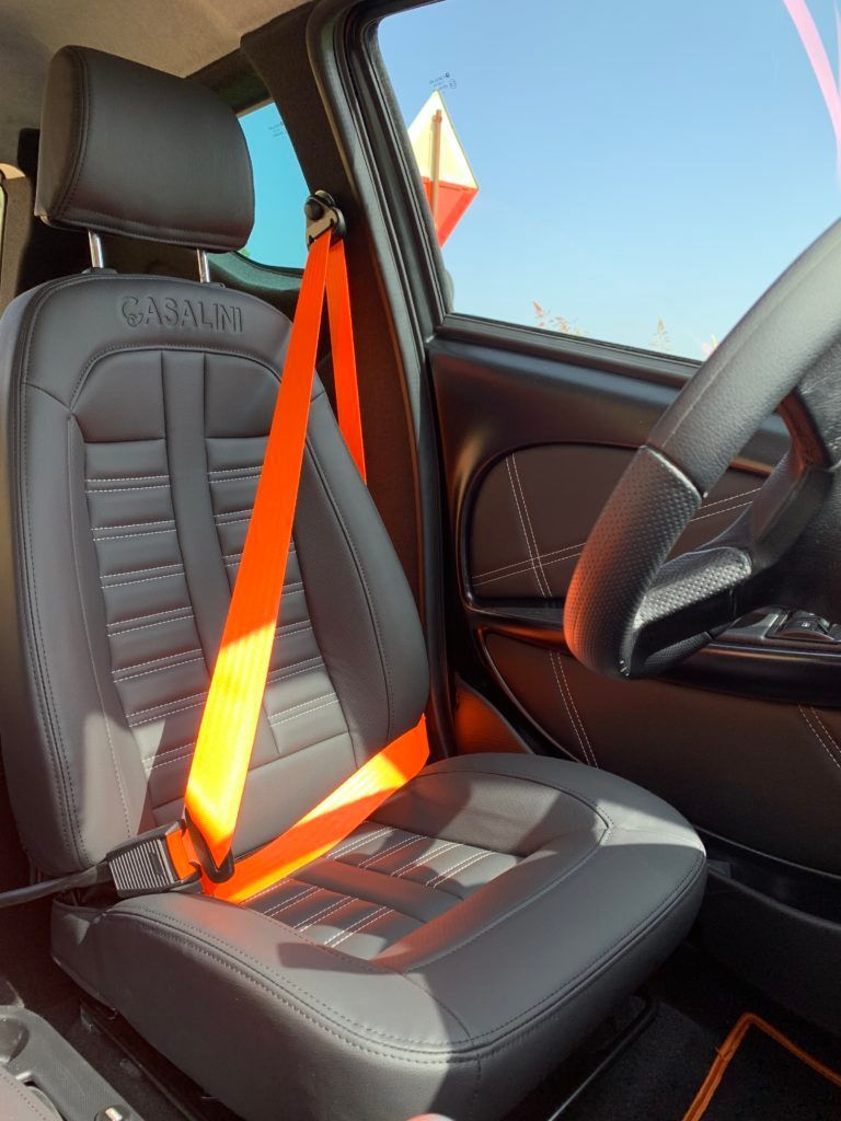 Un seggiolino auto grigio con una cintura di sicurezza arancione