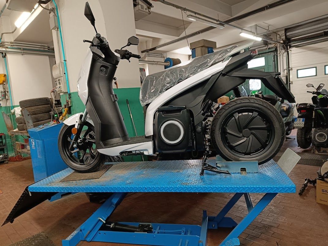 Uno scooter è parcheggiato sopra un ascensore blu in un garage.