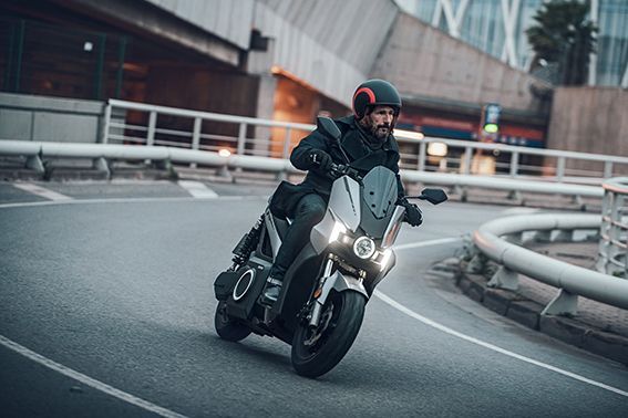 Un uomo sta guidando uno scooter lungo una strada cittadina.