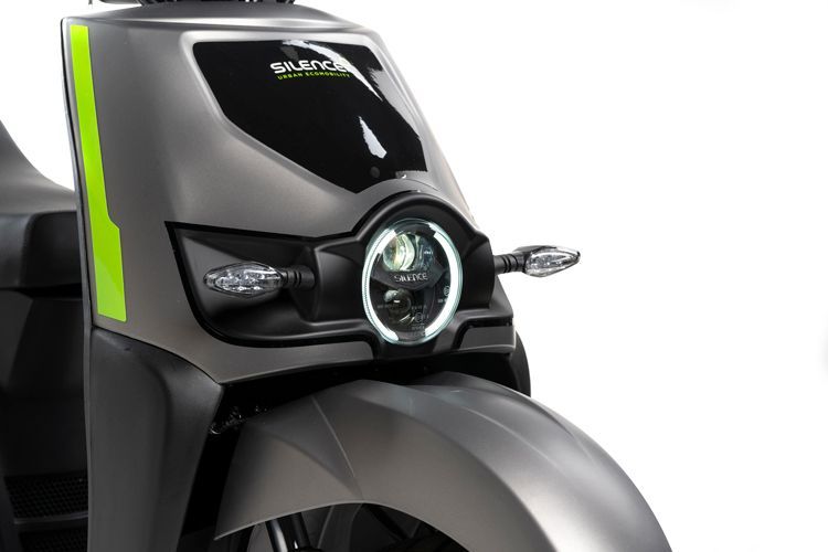 Un primo piano del faro di uno scooter su uno sfondo bianco.