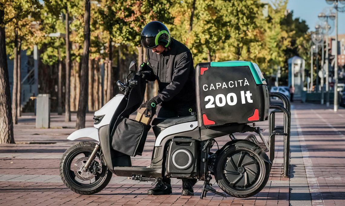 Un uomo sta guidando uno scooter elettrico su un marciapiede.