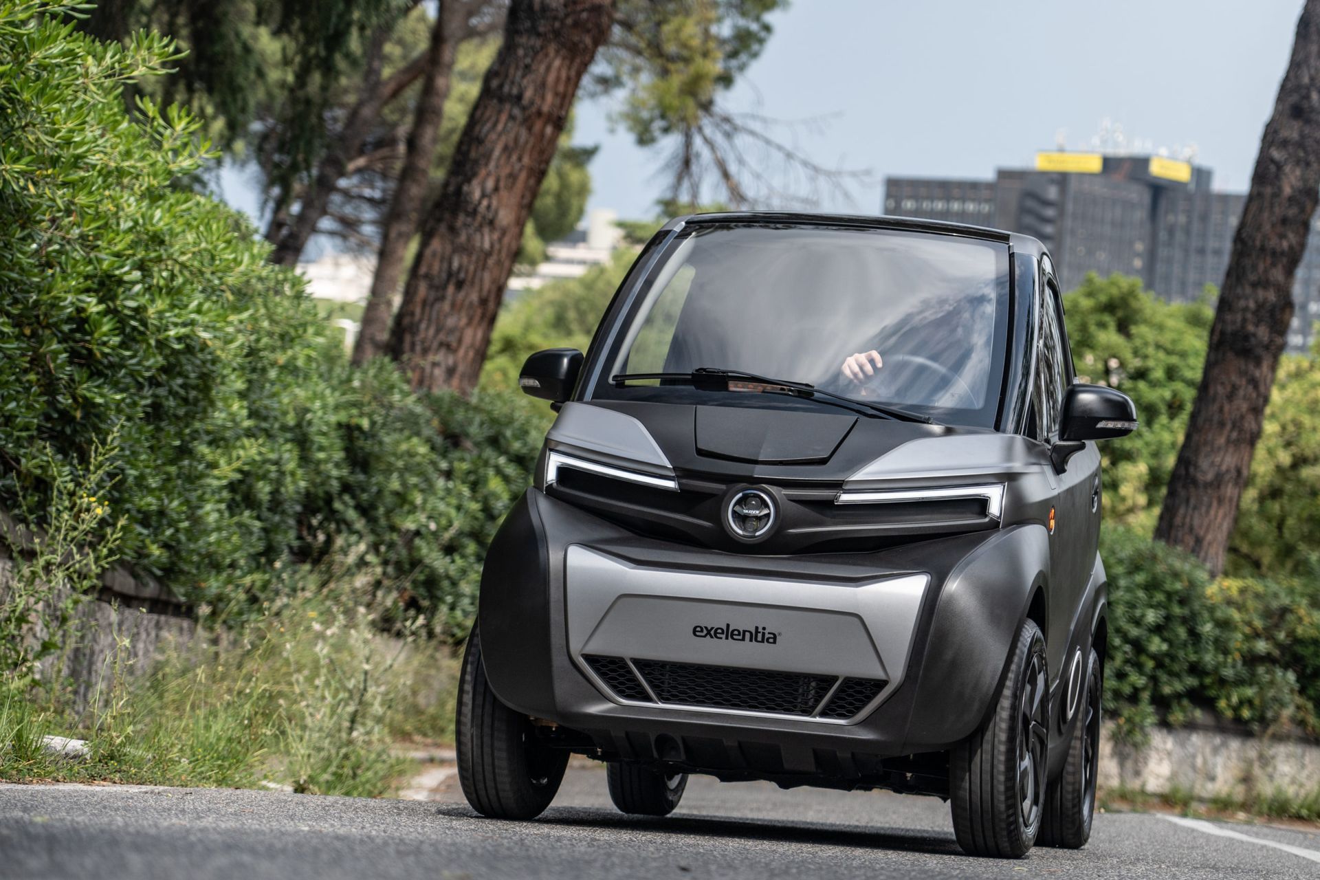 Una piccola auto elettrica sta percorrendo una strada tra gli alberi.