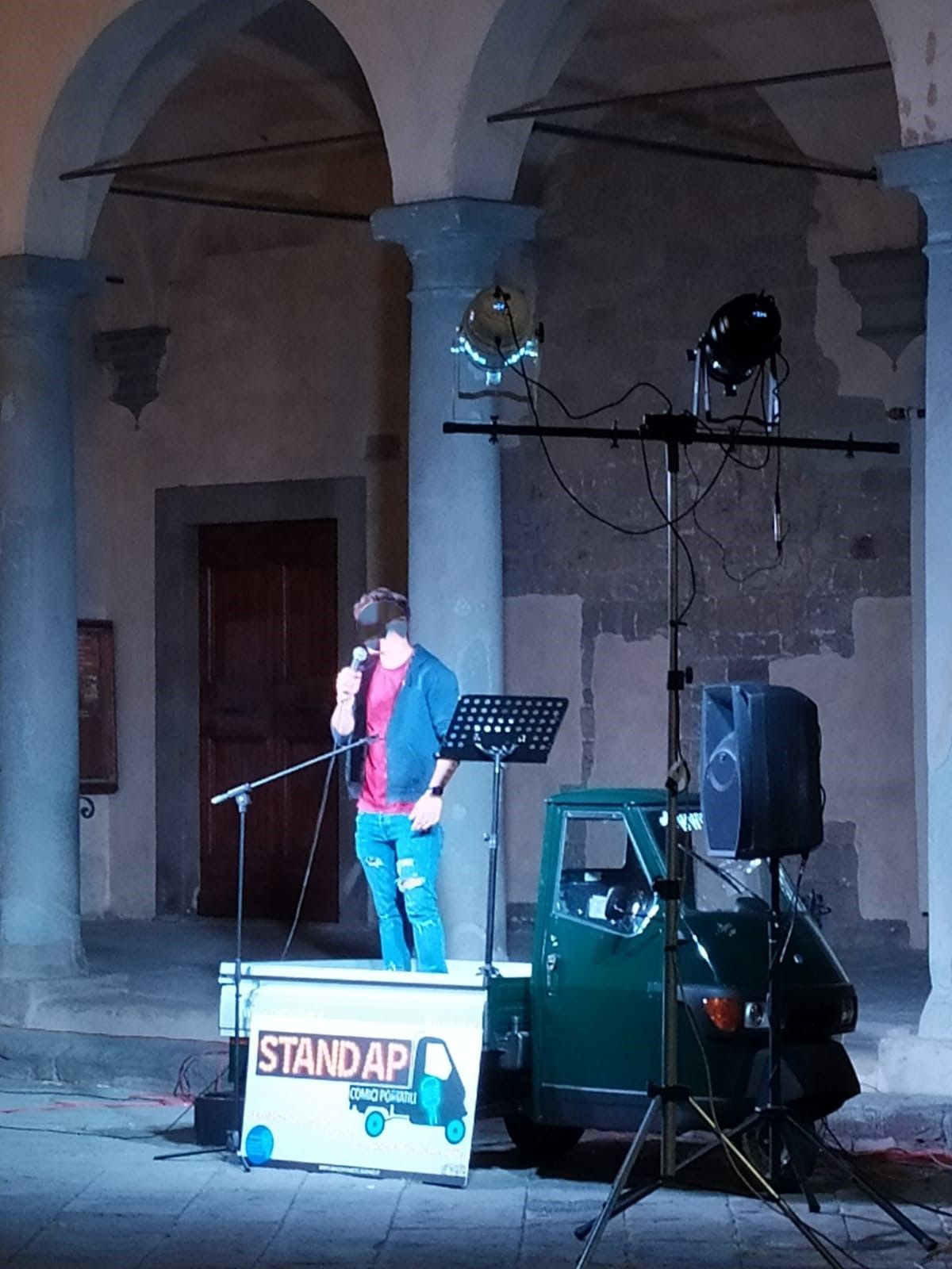 Un uomo che canta in un microfono davanti a un supporto che dice standap