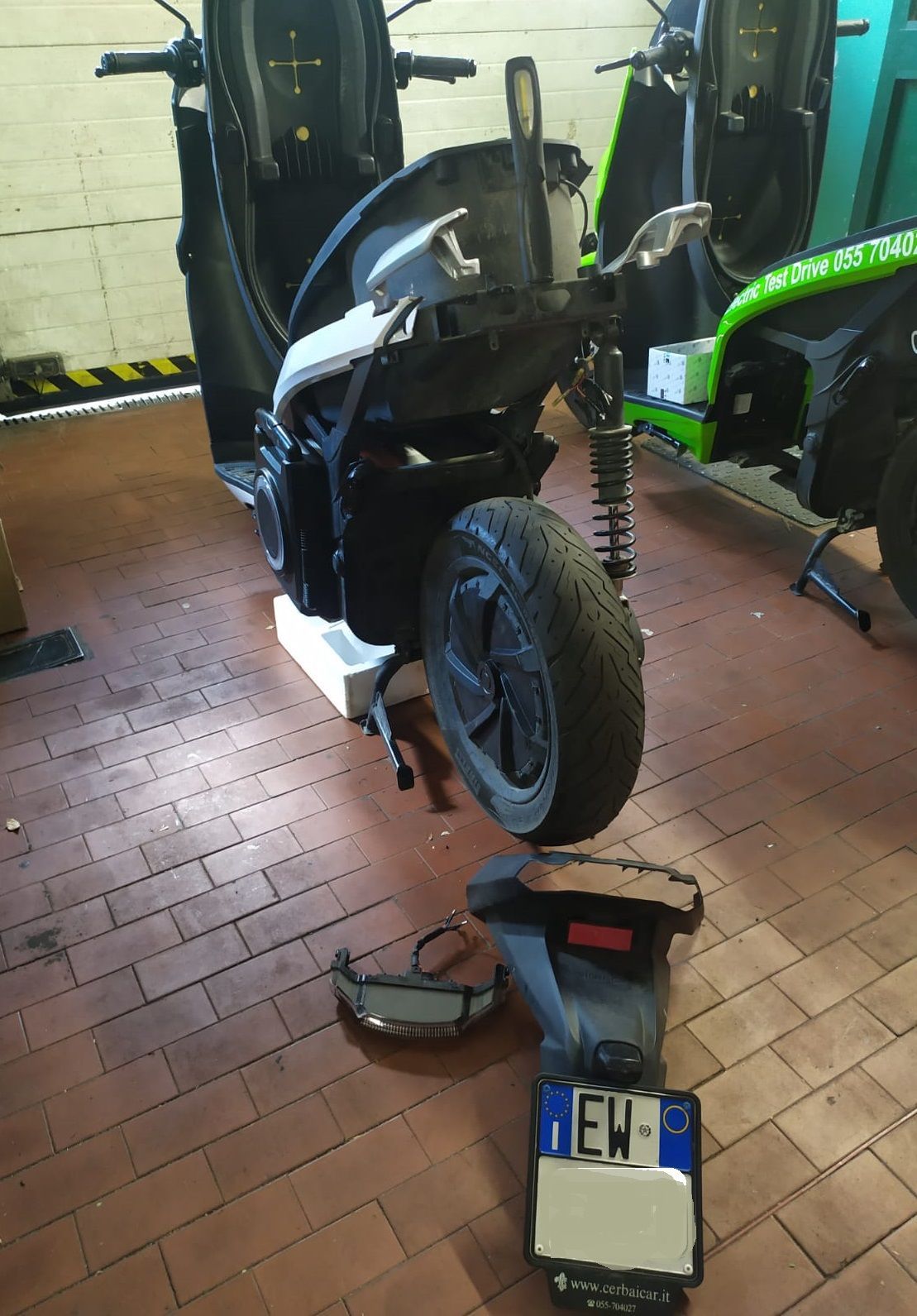 Una motocicletta è parcheggiata su un pavimento di mattoni in un garage.