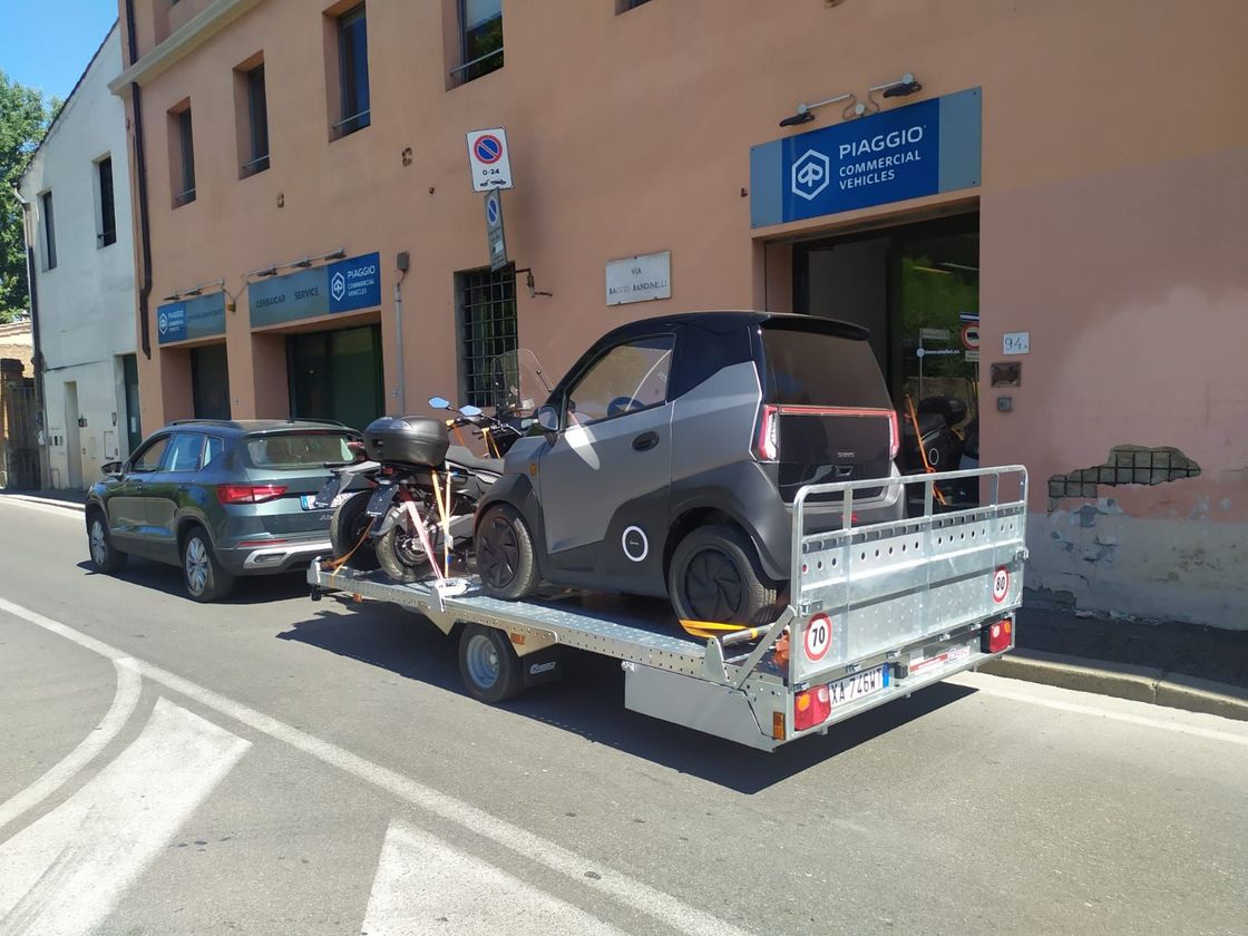 Una piccola automobile viene trainata da un rimorchio.