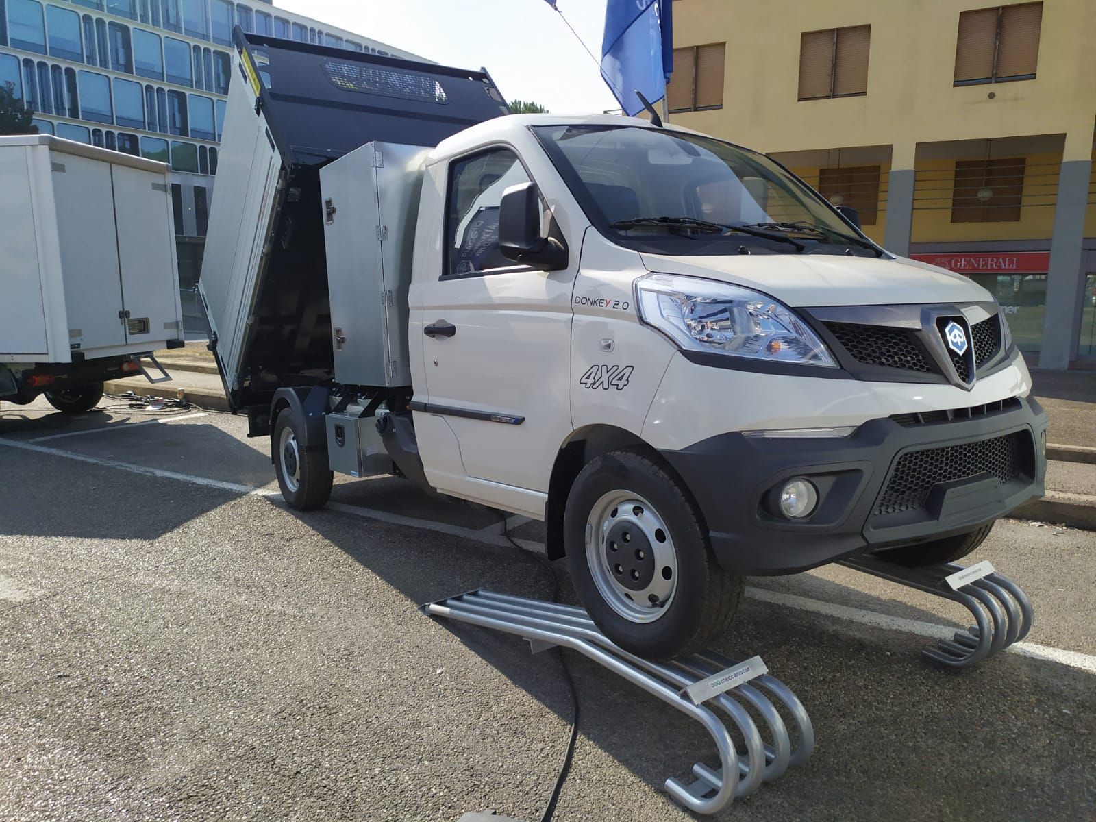 Un camion bianco è parcheggiato sul ciglio della strada, accanto a un edificio.