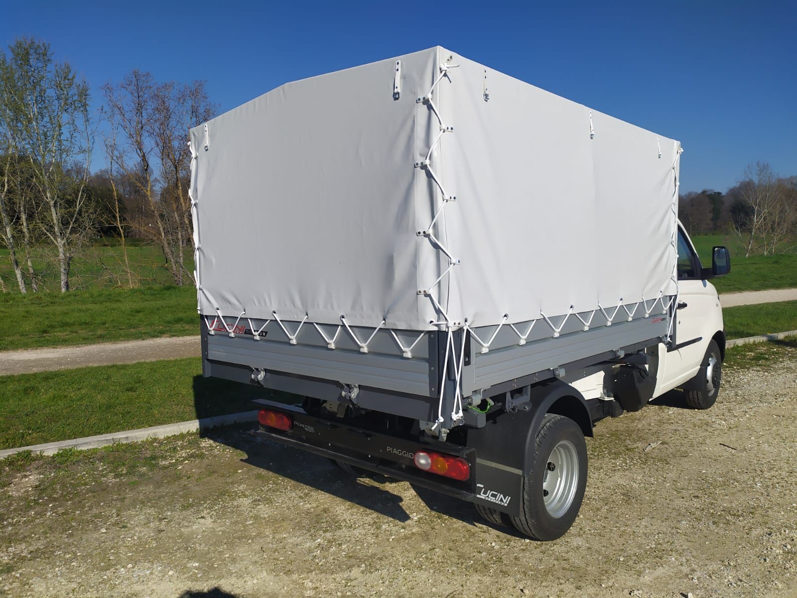 Un camion bianco con un tettuccio sopra è parcheggiato su una strada sterrata.