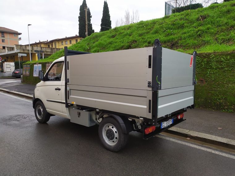 Un camion bianco con cassone ribaltabile è parcheggiato sul ciglio della strada.