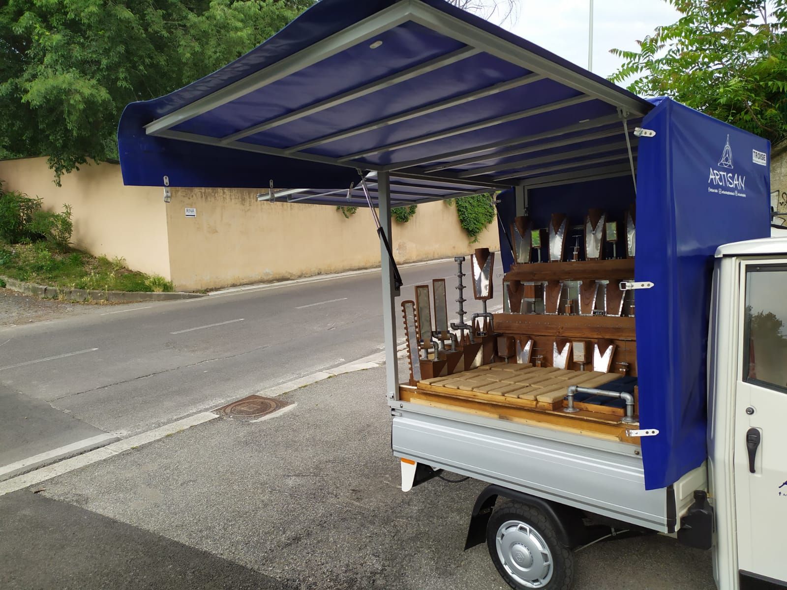 Un camion bianco con una tenda blu è parcheggiato sul ciglio della strada.