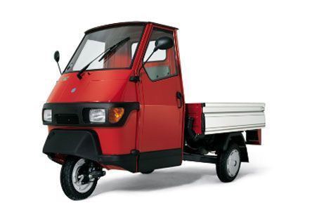 Un veicolo rosso a tre ruote con un cassone bianco su uno sfondo bianco.