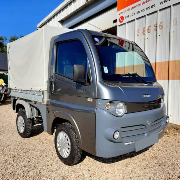 Un camion grigio con una tettoia bianca è parcheggiato davanti a un edificio