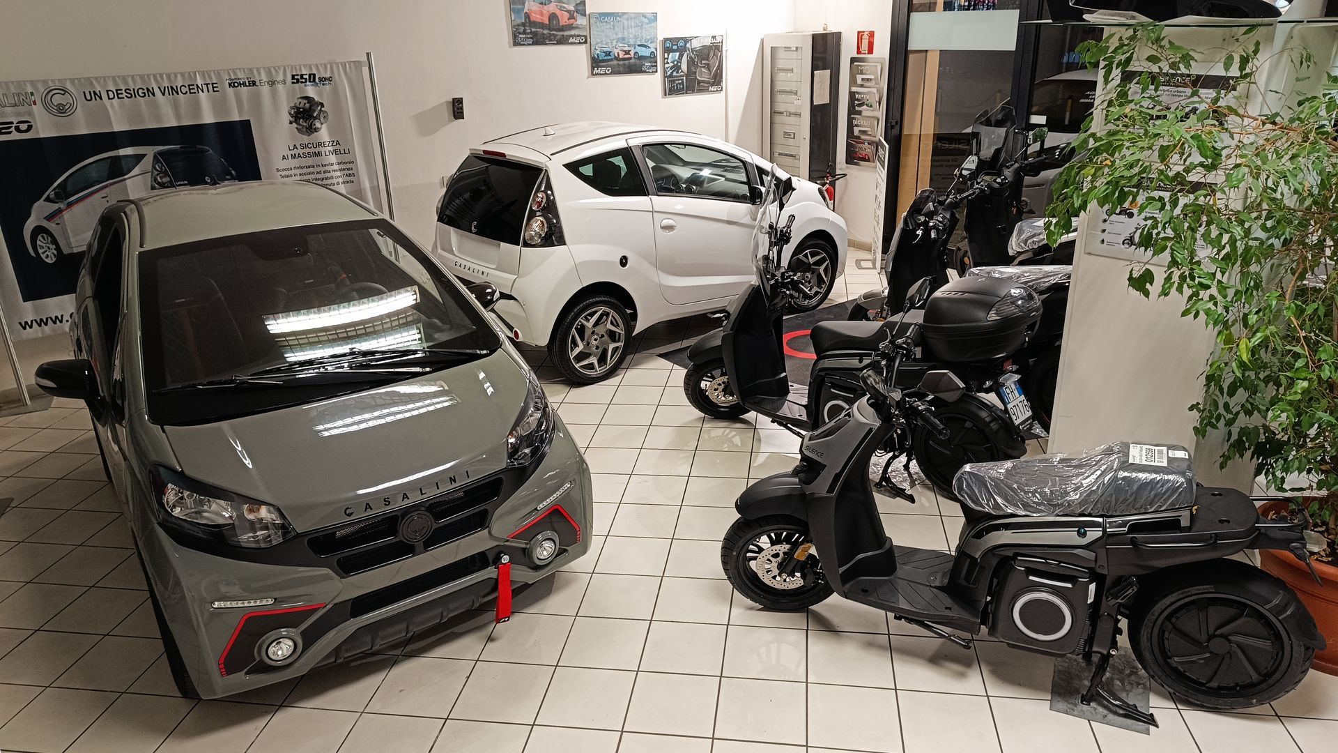 Un'auto e uno scooter sono parcheggiati in uno showroom.
