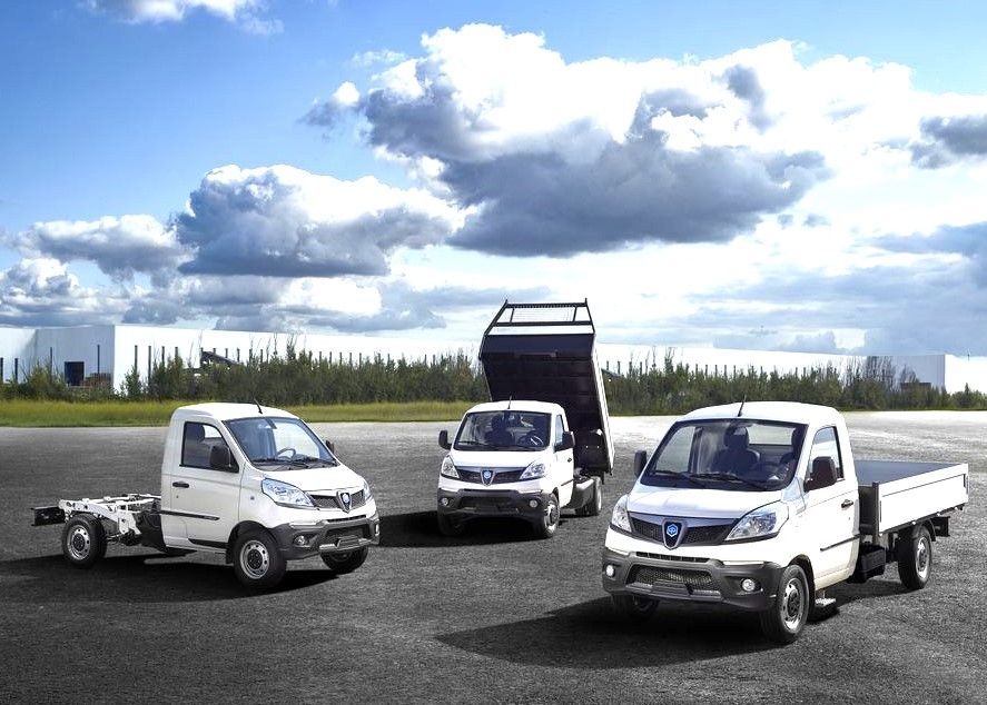 Tre camion bianchi sono parcheggiati uno accanto all'altro su una strada.