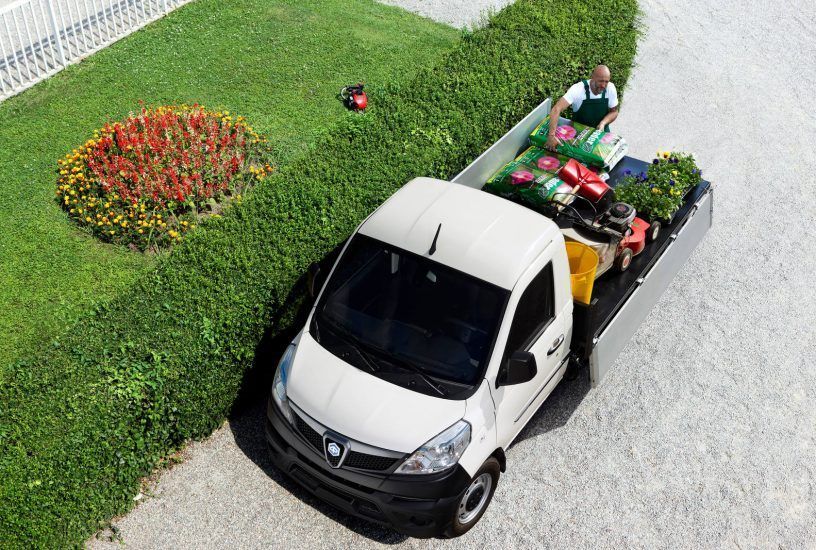 Un furgone bianco con un giardiniere sul retro è parcheggiato nel vialetto.