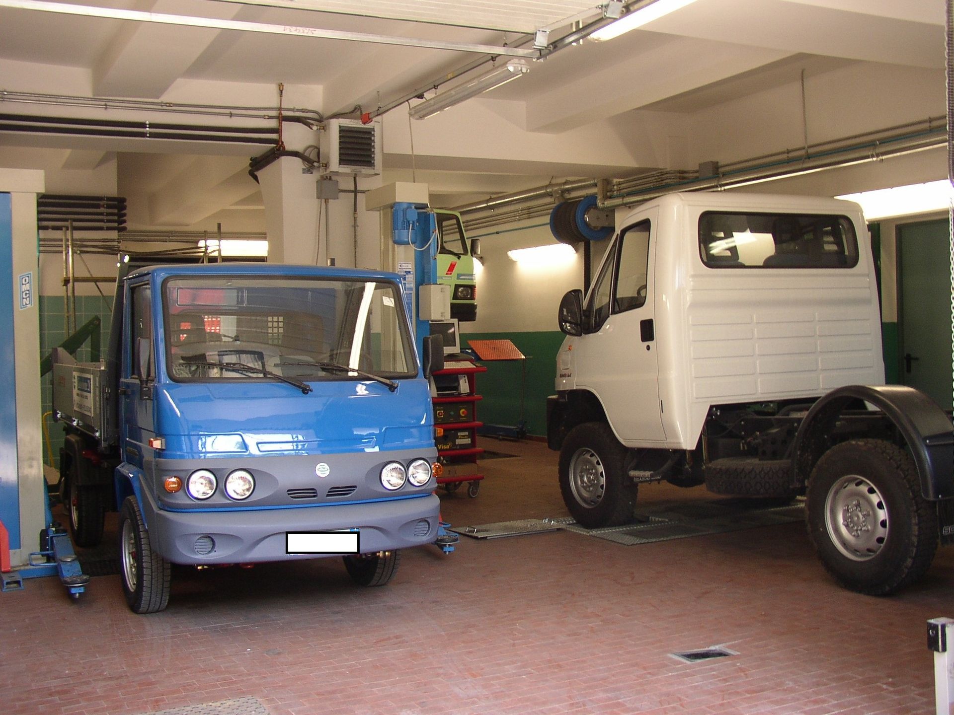 Un camion blu è parcheggiato accanto a un camion bianco in un garage