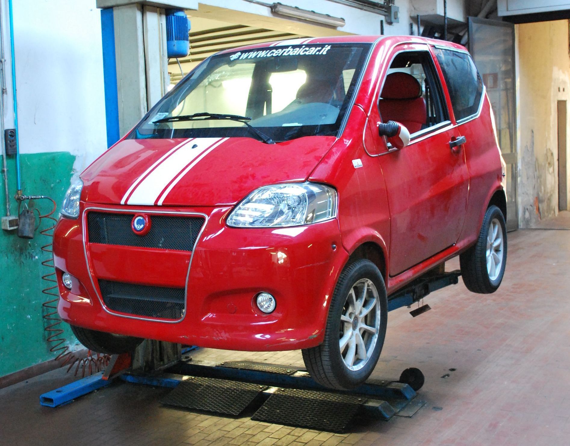 Una piccola macchina rossa è su un ascensore in un garage