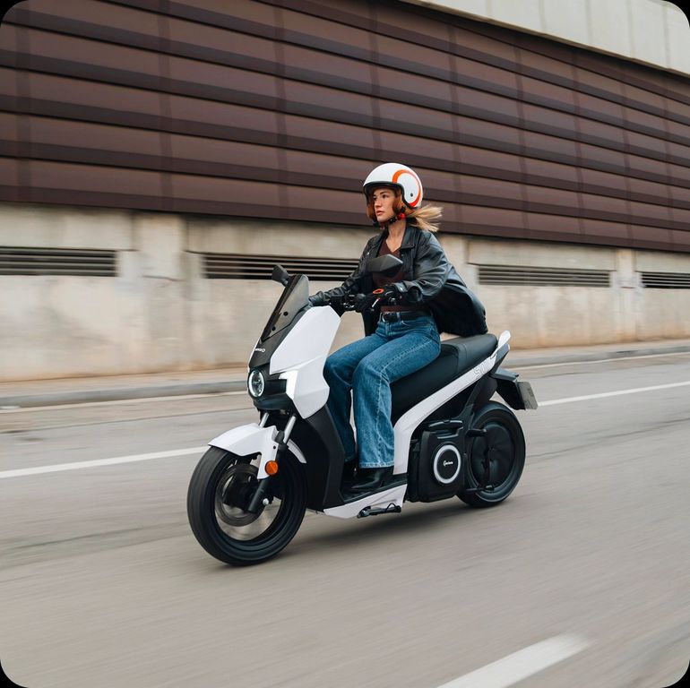 Una donna sta guidando un monopattino elettrico lungo una strada.