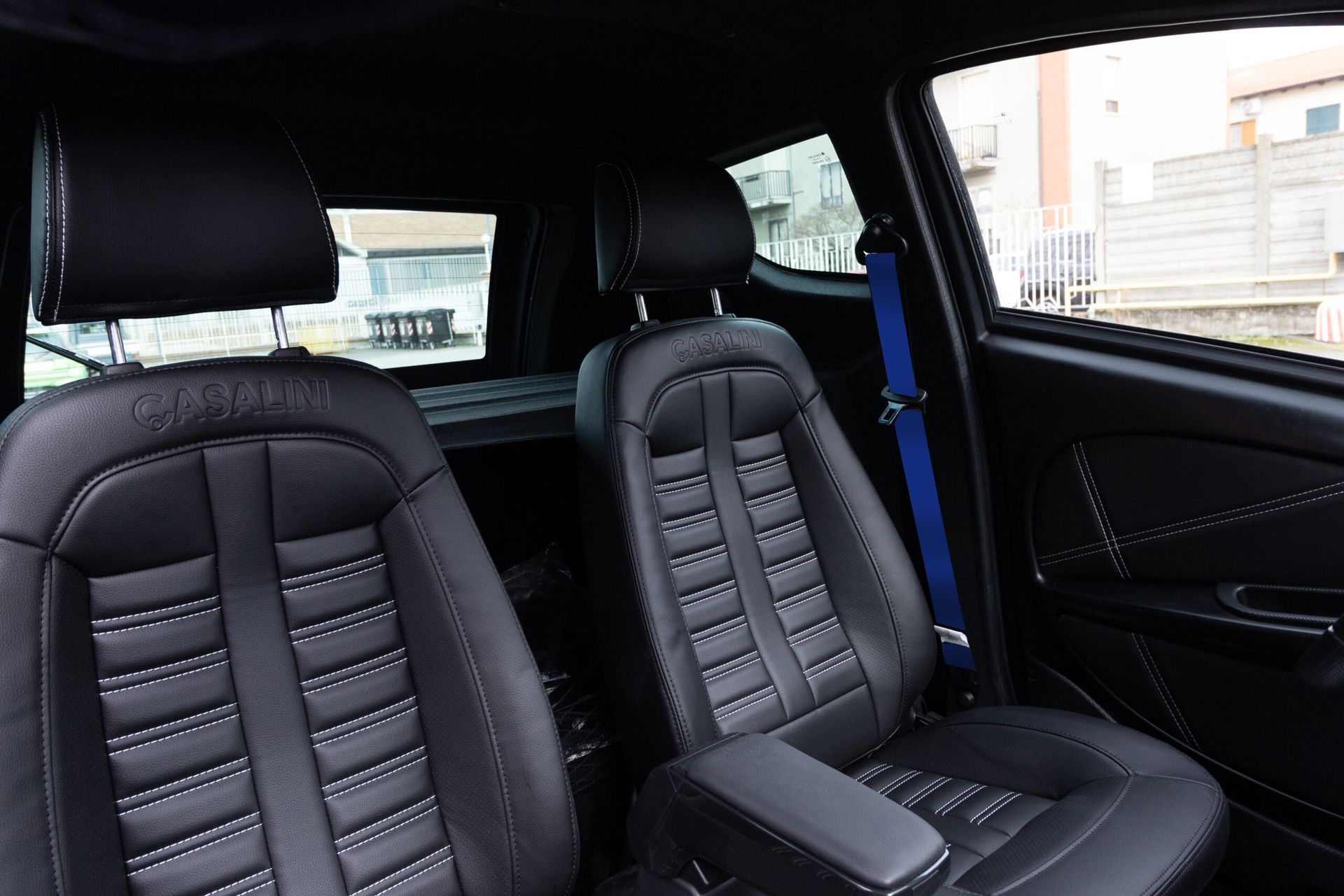 L'interno di un'auto con sedili in pelle nera e cintura di sicurezza blu.