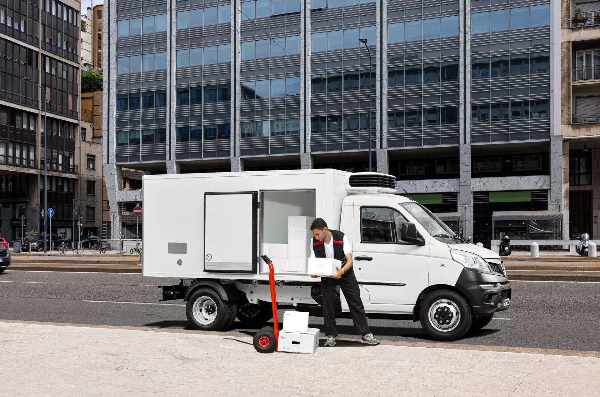 Un uomo sta caricando delle scatole su un furgone bianco su una strada cittadina.