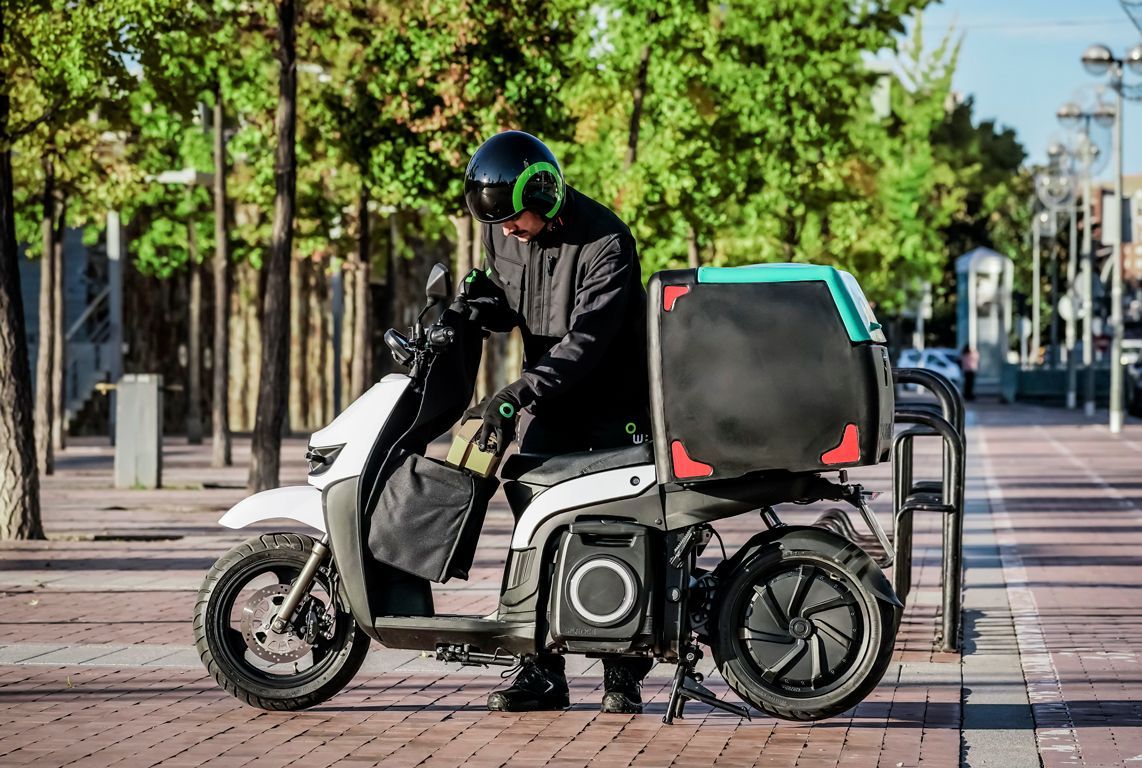Un uomo sta guidando uno scooter elettrico su un marciapiede.