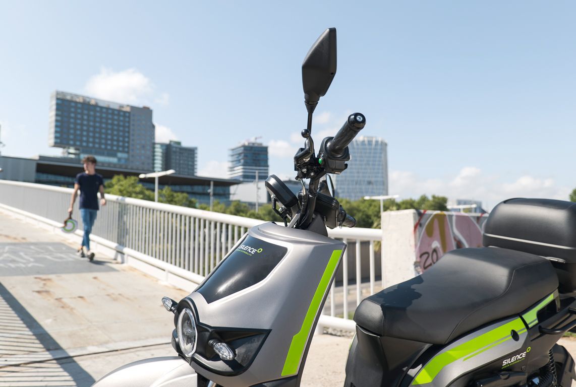 Un uomo sta attraversando un ponte accanto a uno scooter.