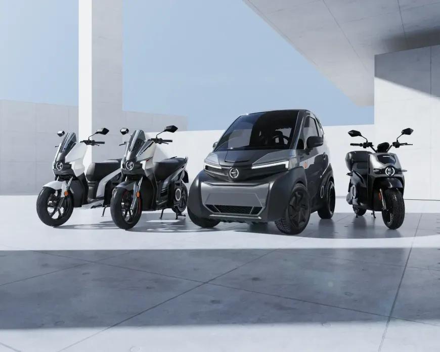 Tre motociclette e un'auto sono parcheggiate una accanto all'altra in un parcheggio.