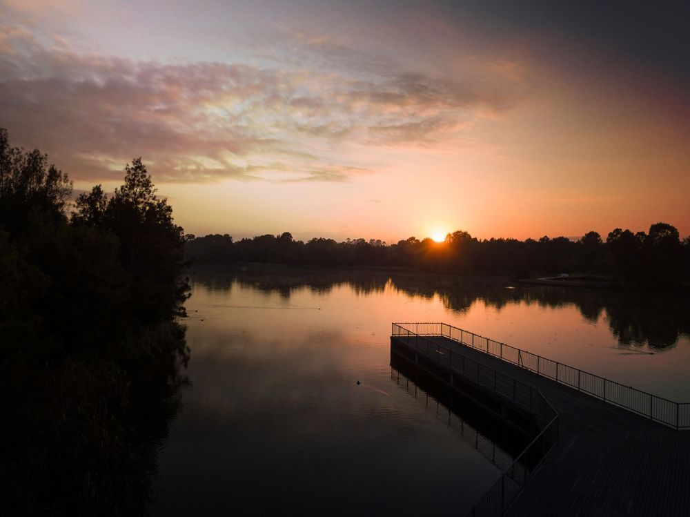The Sun Is Setting Over a Lake with A Dock in The Foreground — Revive Air Conditioning in Narellan, NSW