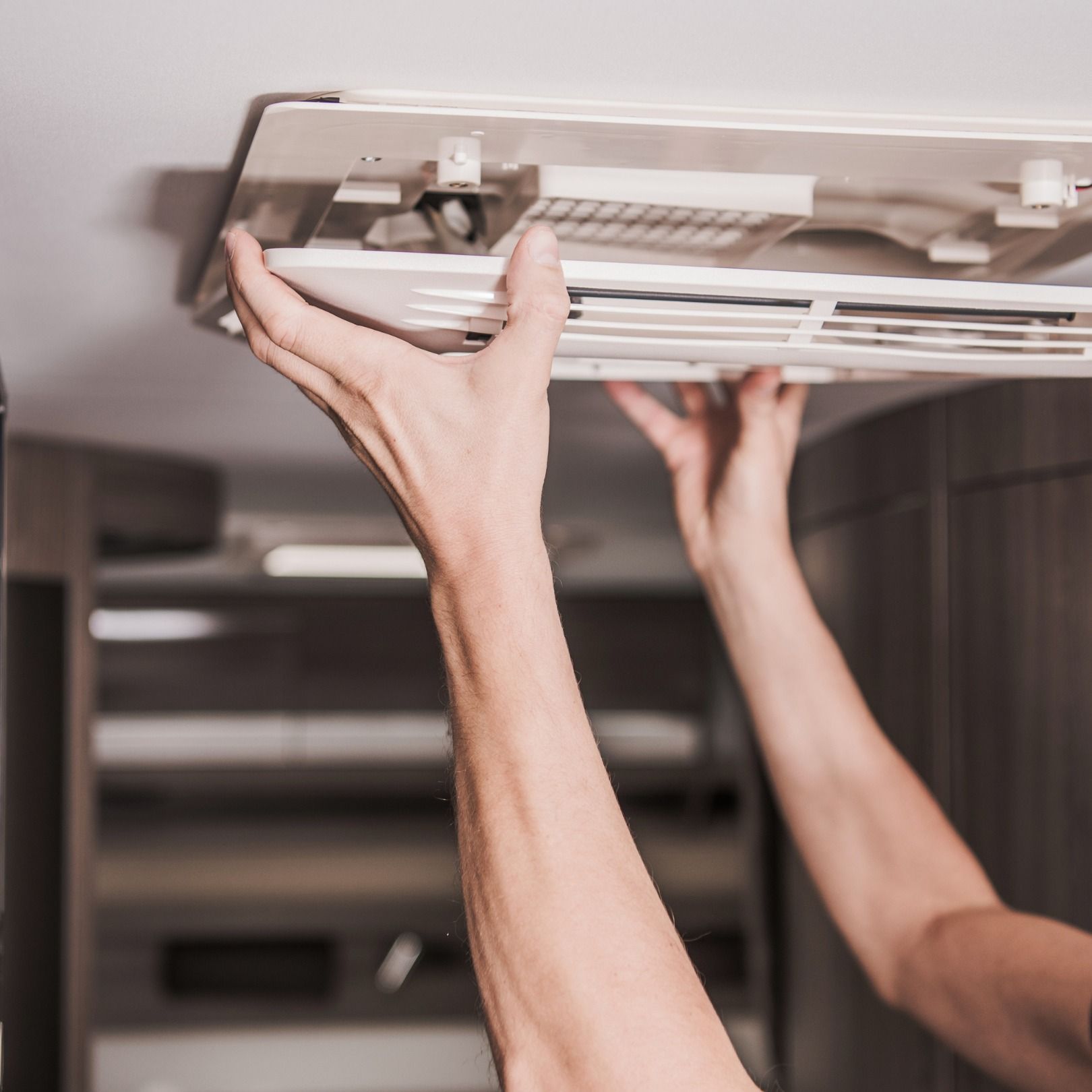 A Man Is Fixing a ducted  Air Conditioner  — Revive Air Conditioning in Campbelltown, NSW