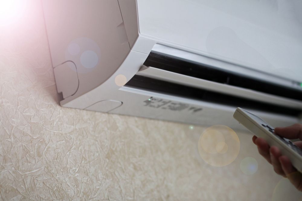 A Person Is Using a Remote Control to Turn on An Air Conditioner — Revive Air Conditioning in Oran Park, NSW
