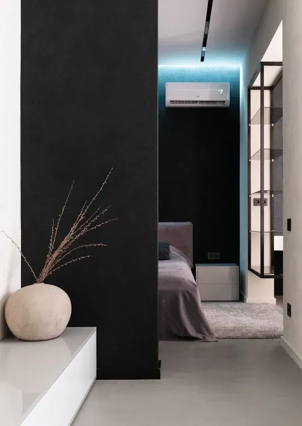 A Man is Installing an Air Conditioner on a Wall — Revive Air Conditioning in Camden, NSW