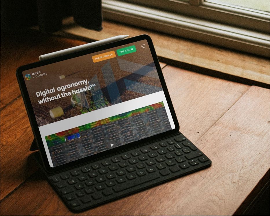 Tablet with keyboard on a wooden desk beside a window, showing a website on its screen