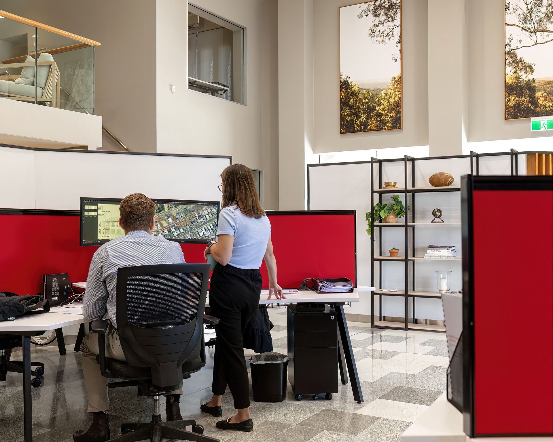 Office workers at desks with red privacy panels in a bright open workspace