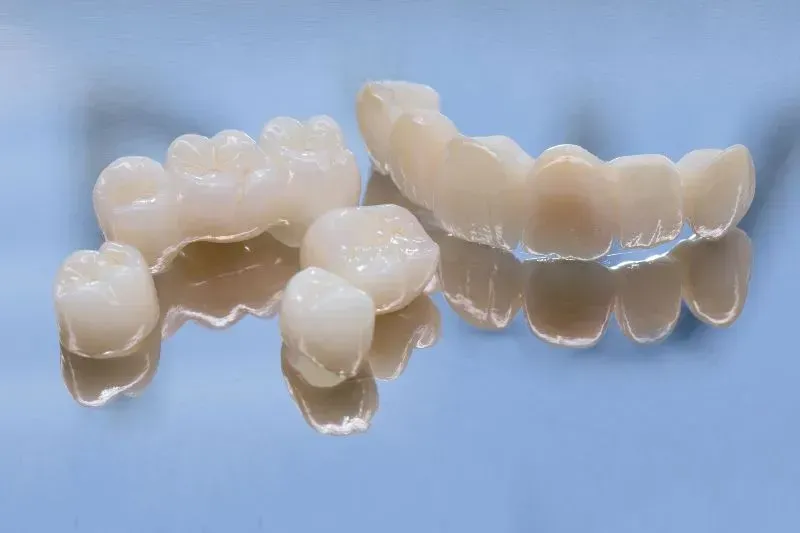 Zirconia dental crowns , white, on a reflective blue surface.