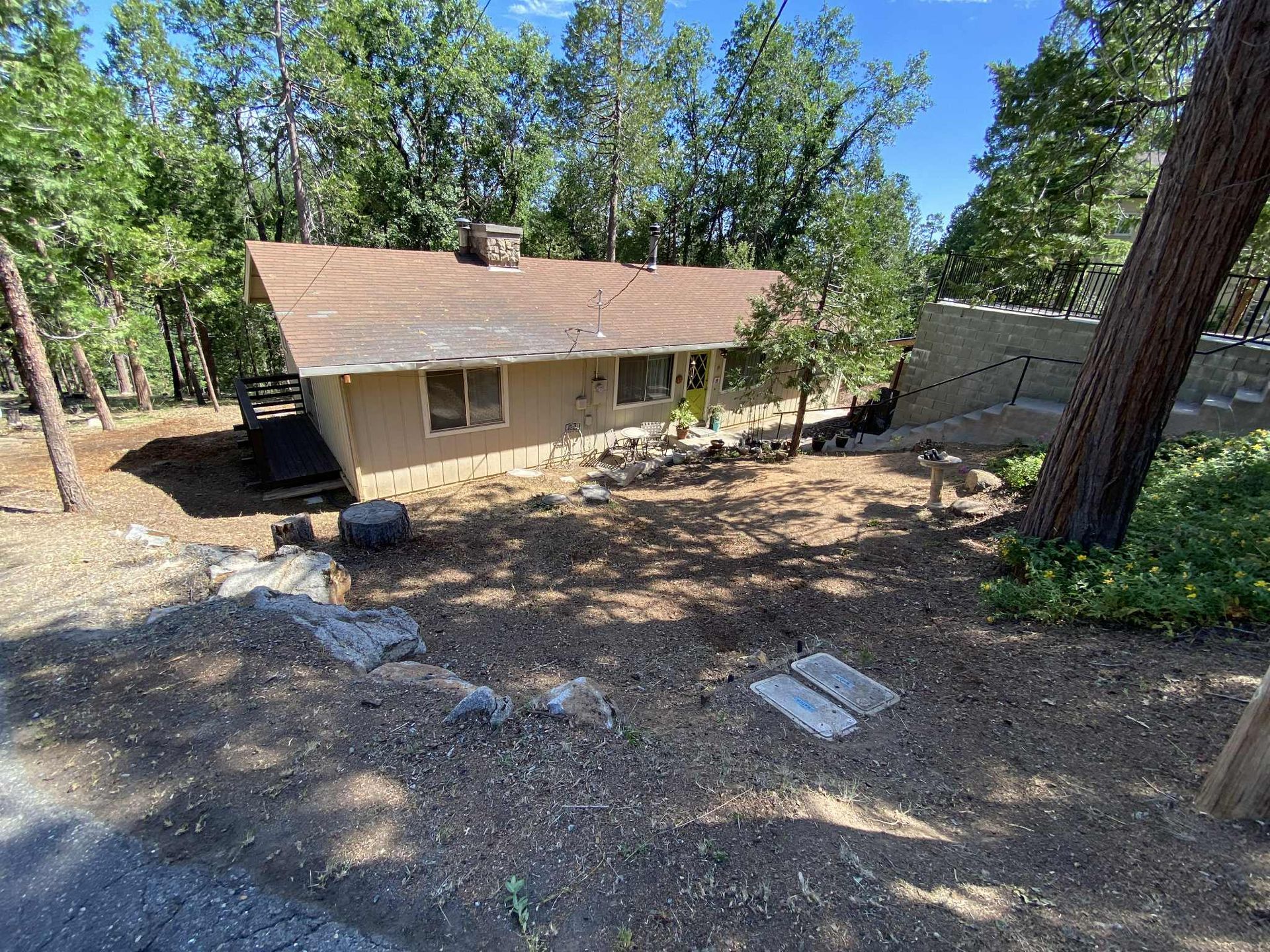A low-slung, tan house nestled in a forest setting; brown roof and steps leading up to the entrance.