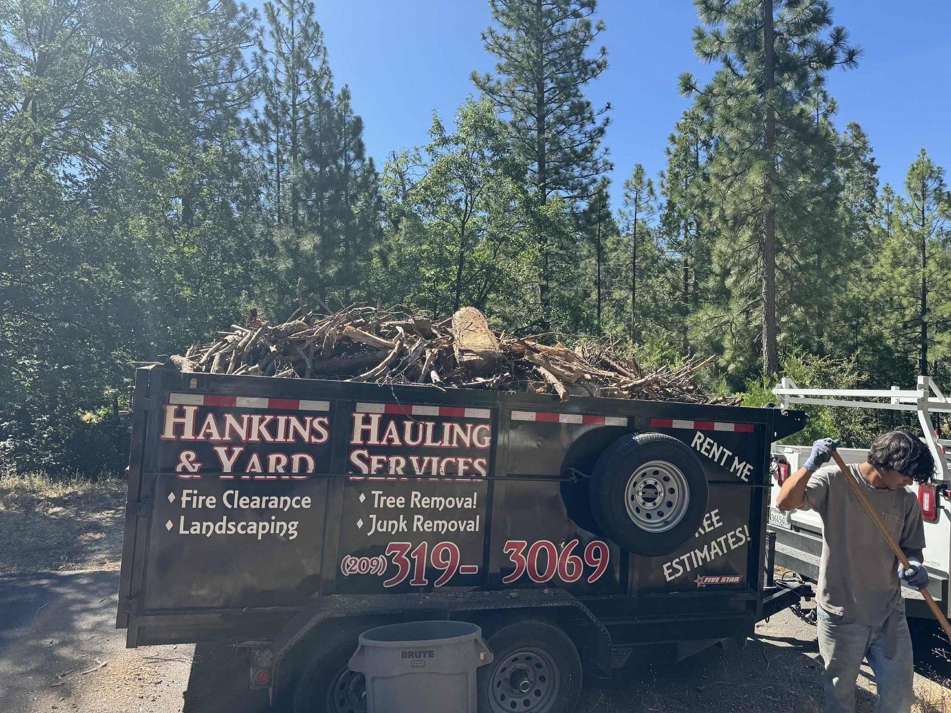 A loaded dump trailer for Hankins Hauling & Yard Services. A person works nearby.