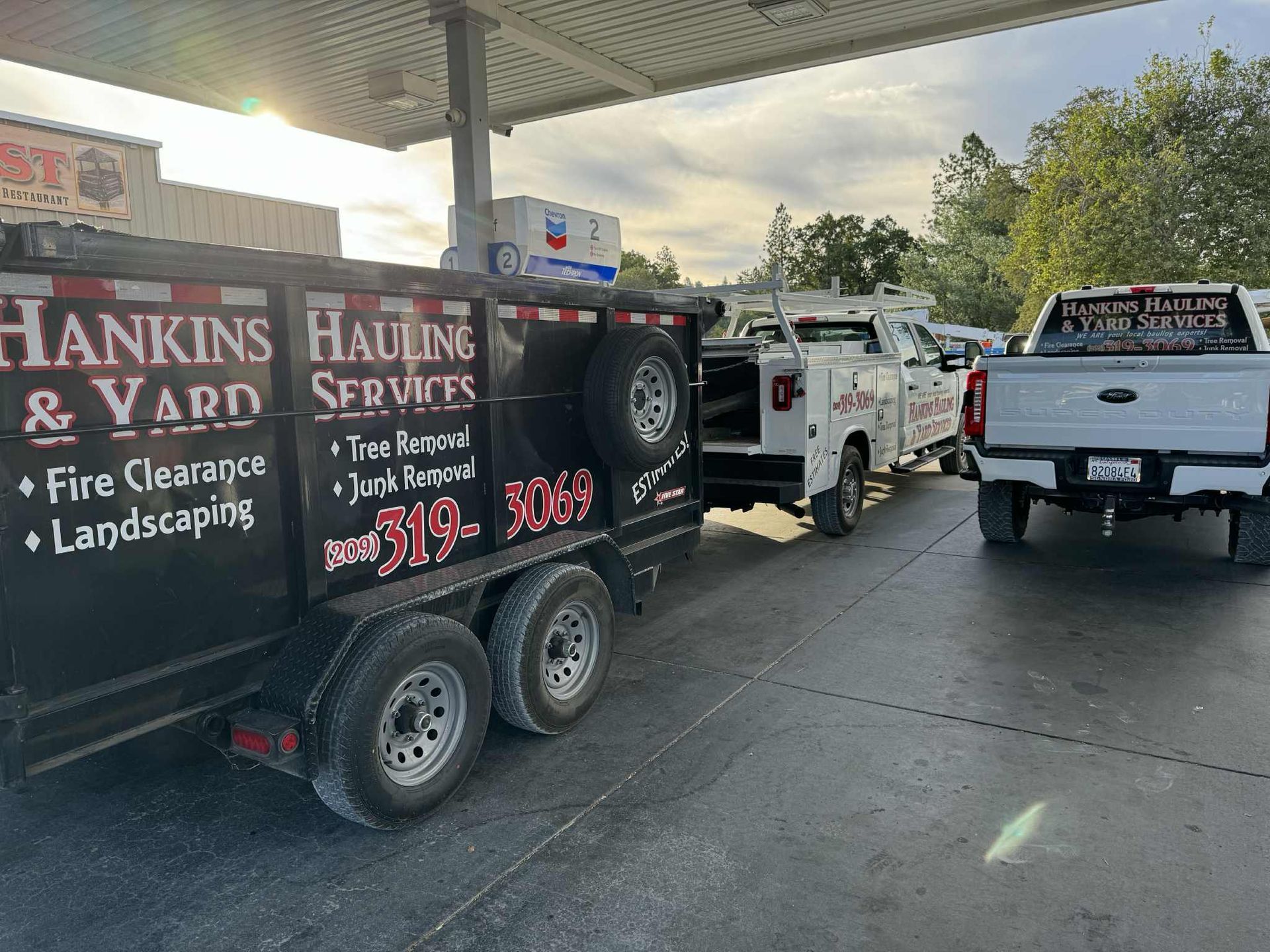 Hankins Hauling & Yard Services trailer and trucks at a gas station, ready for work.