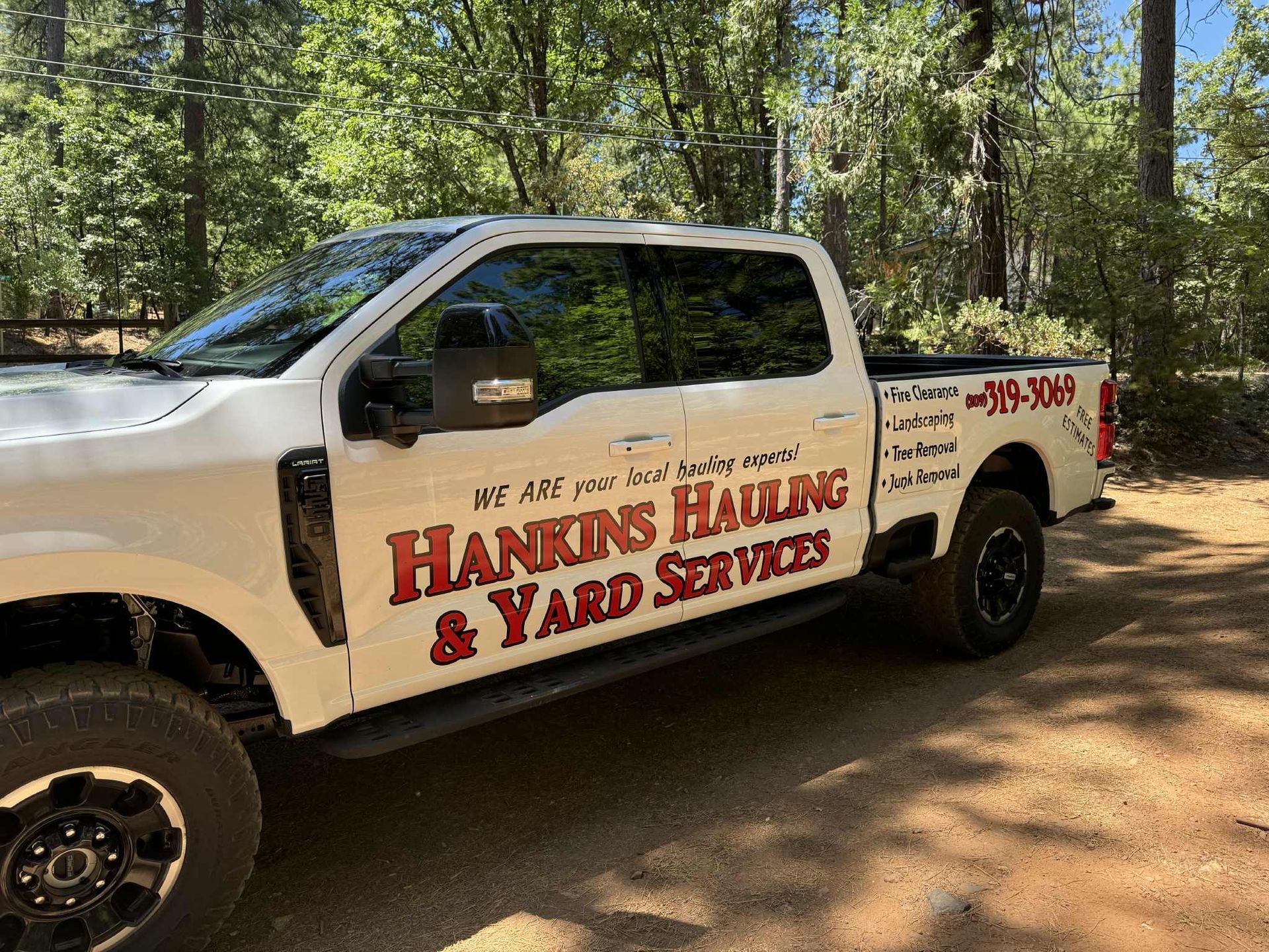 White Hankins Hauling truck parked outdoors. The truck has red lettering with a phone number.