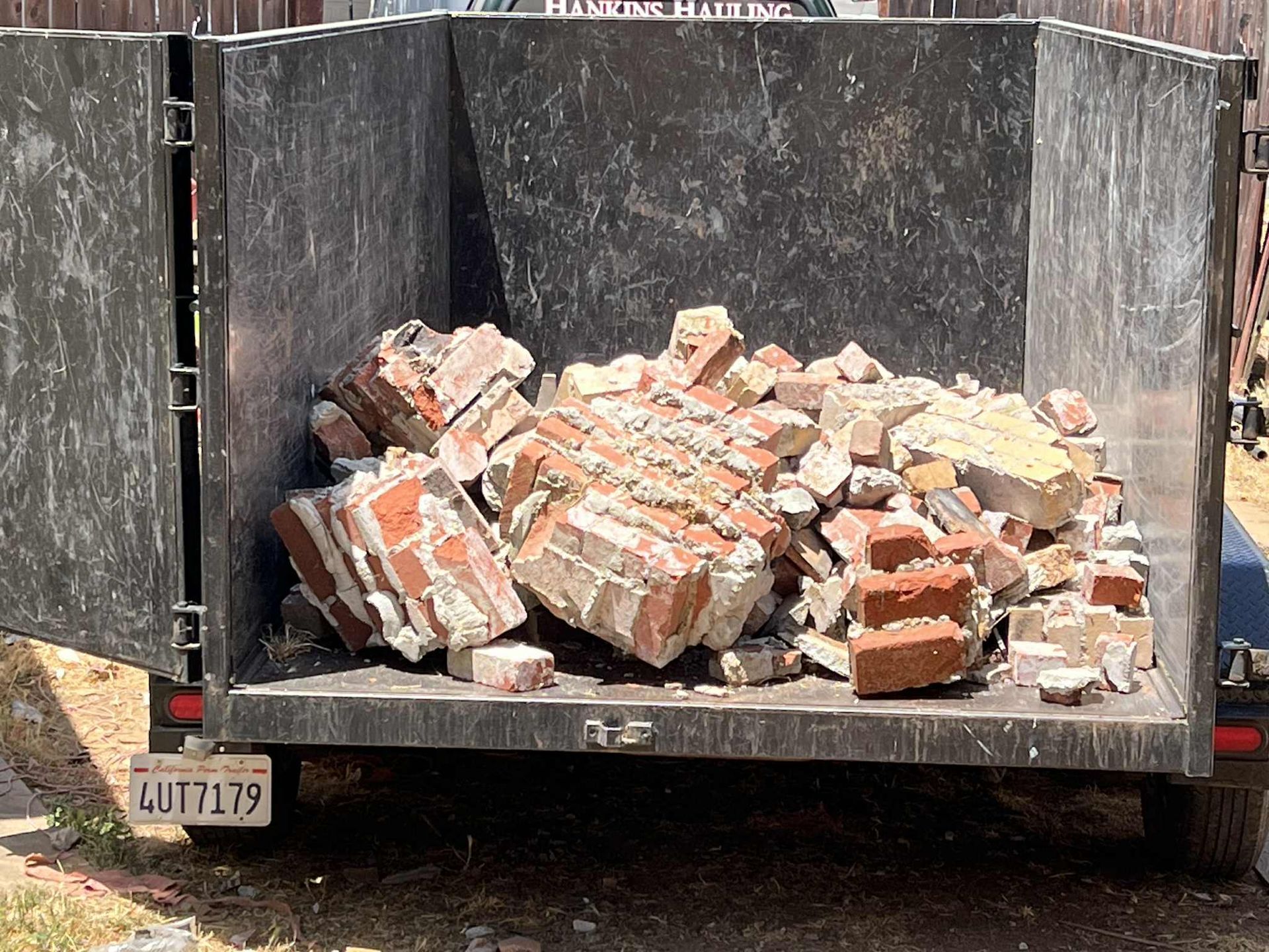 A trailer filled with broken red bricks and concrete debris, likely from demolition, outdoors.