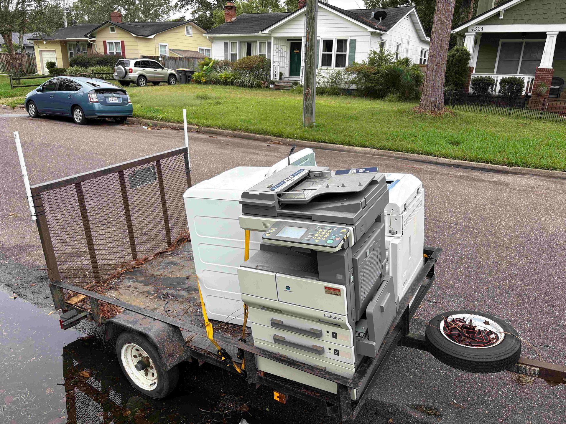 Trailer with office equipment on a residential street. A car is parked nearby.