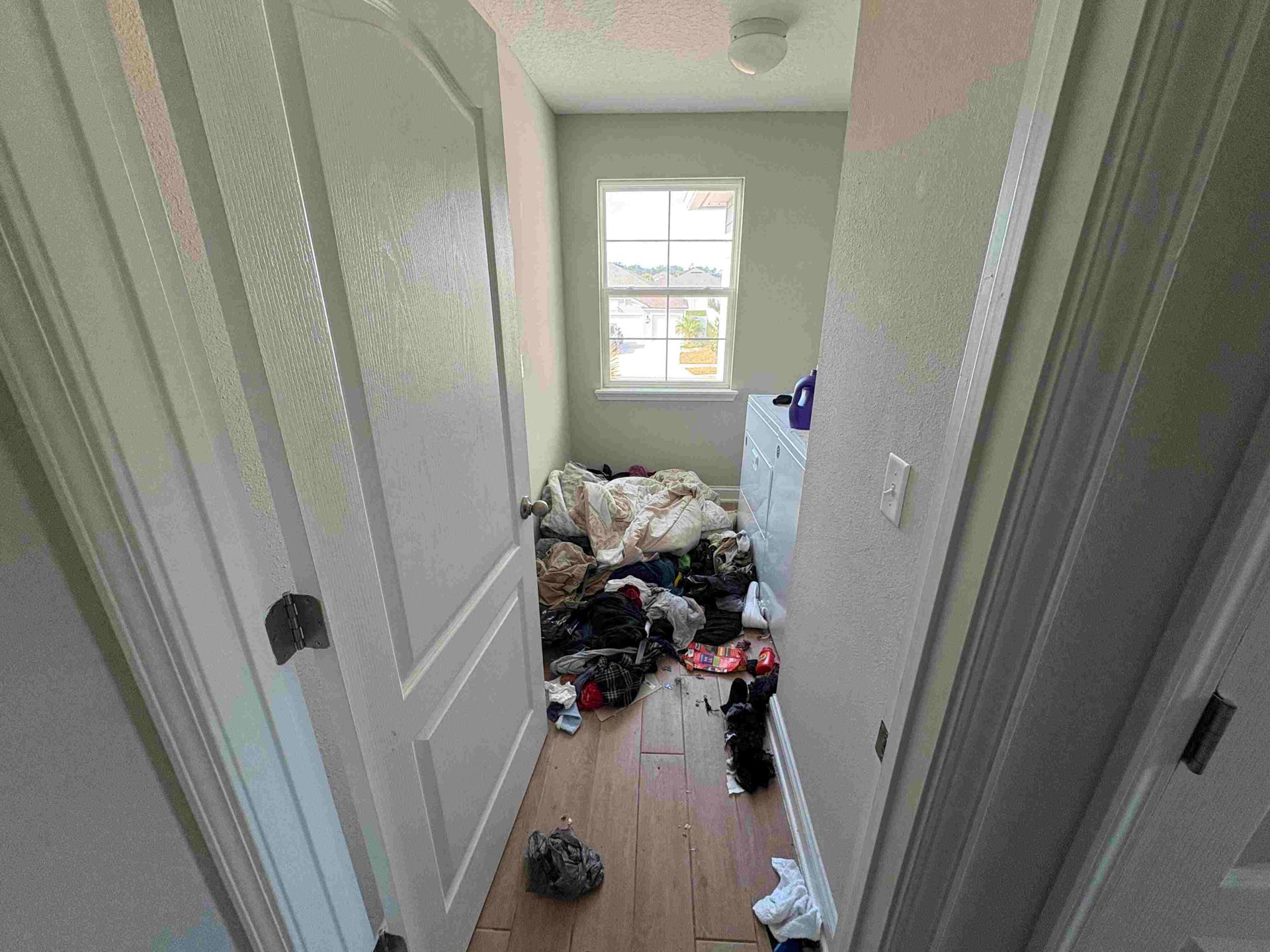 Narrow hallway with a messy pile of clothes and a small window.