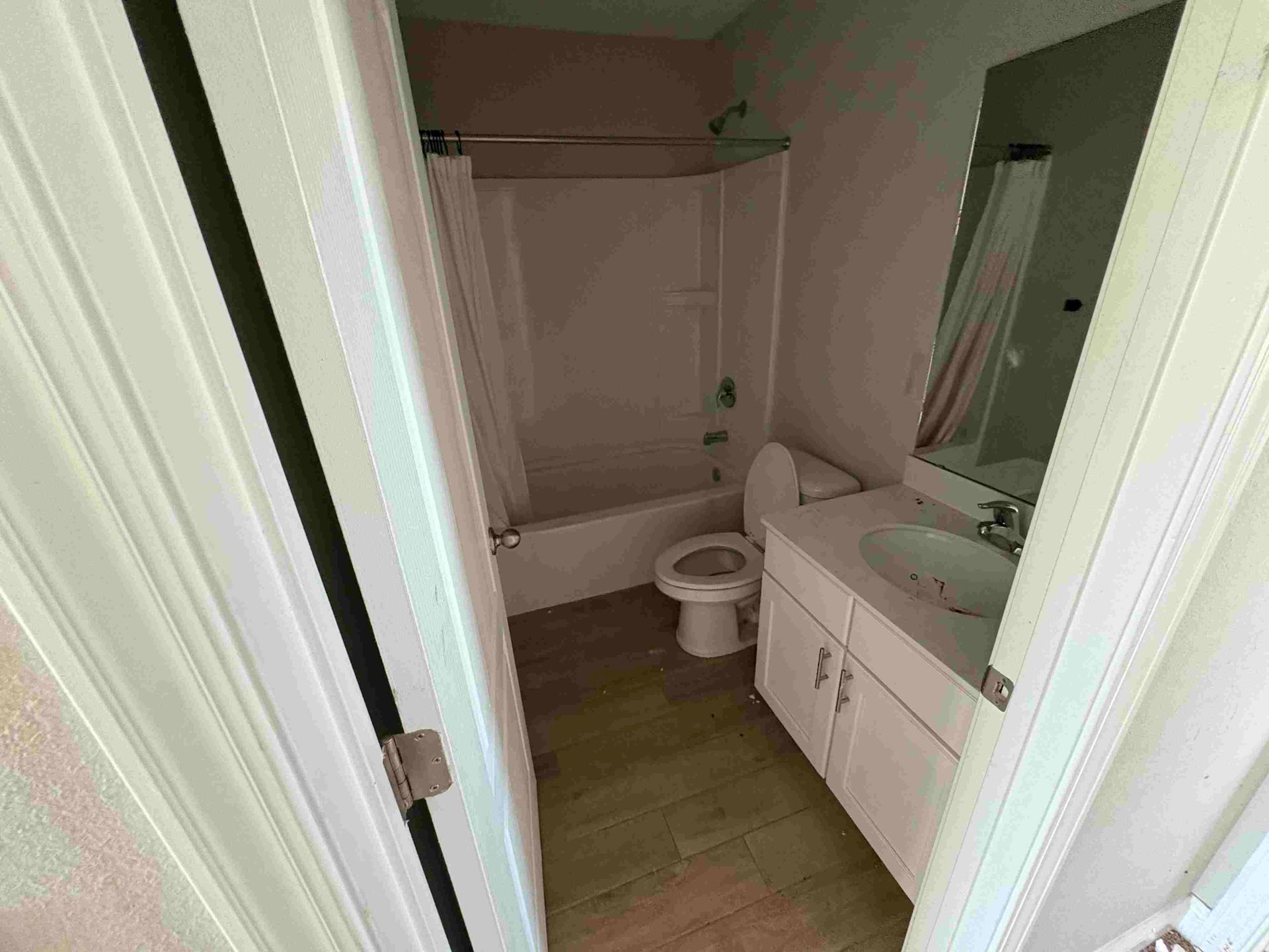 Bathroom with white fixtures: toilet, sink, tub/shower. Beige walls and flooring.