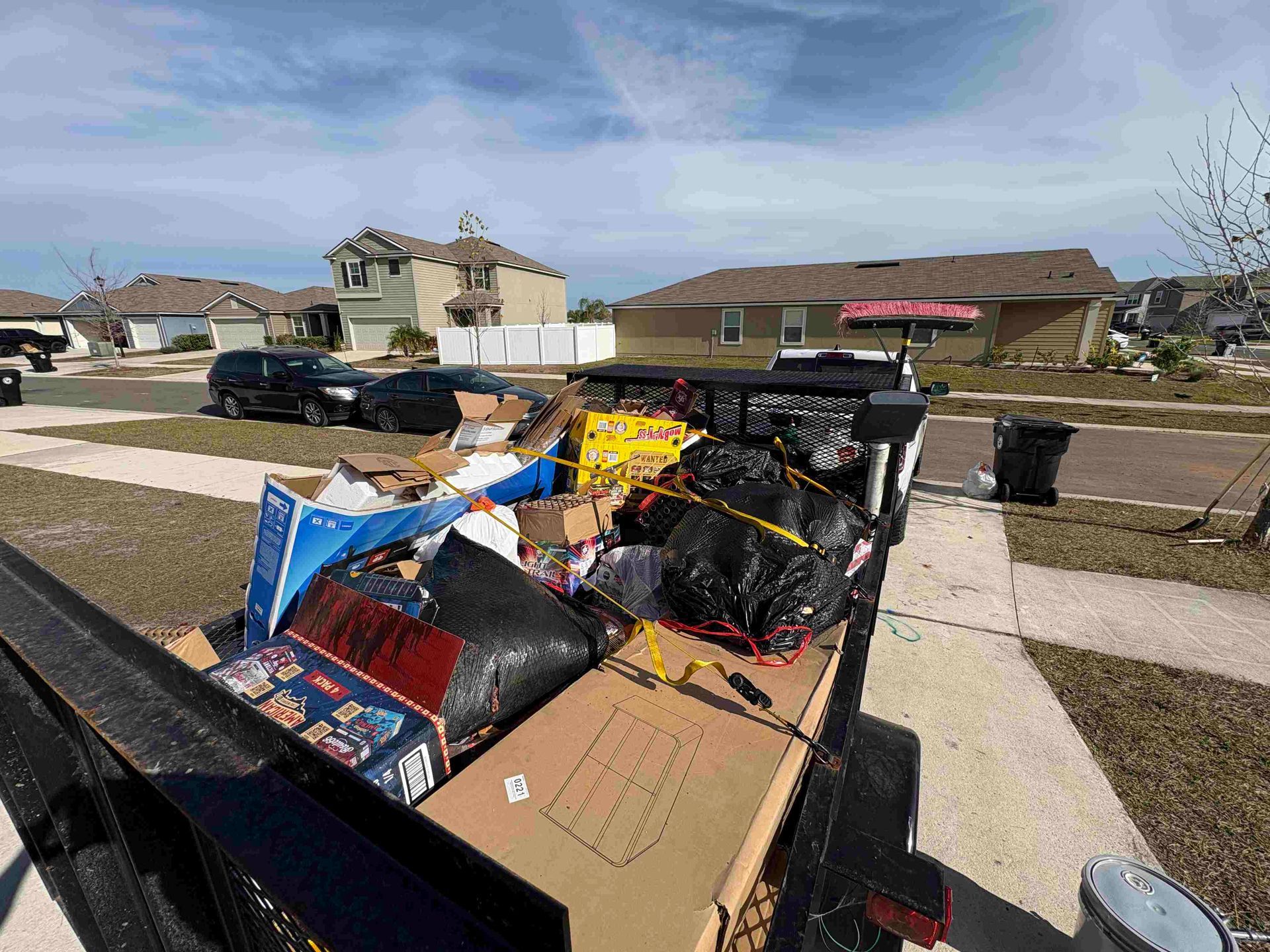 Trailer filled with trash in a suburban neighborhood on a sunny day.