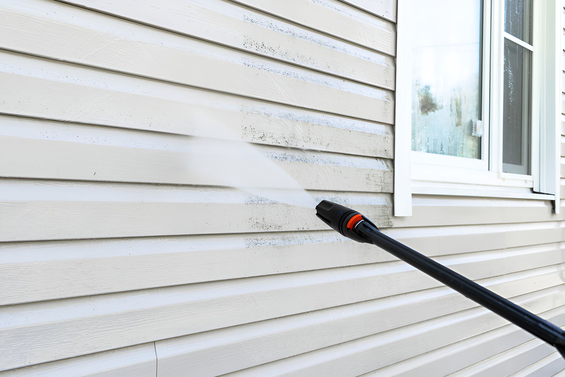 A Person is Cleaning the Side of a House With a High Pressure Washer — First Choice Cleaning Services in Wodonga, VIC