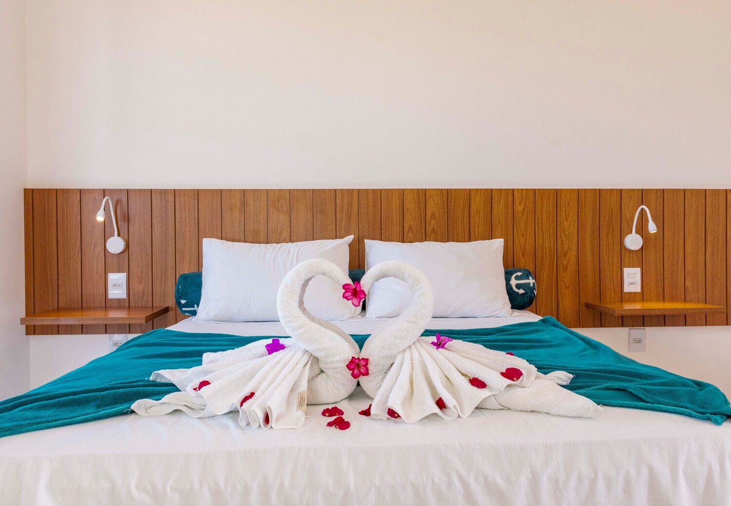 Uma cama com dois cisnes feitos de toalhas.